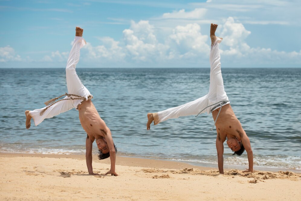 Two men performing capoeira on the beach.
Source: Freepik