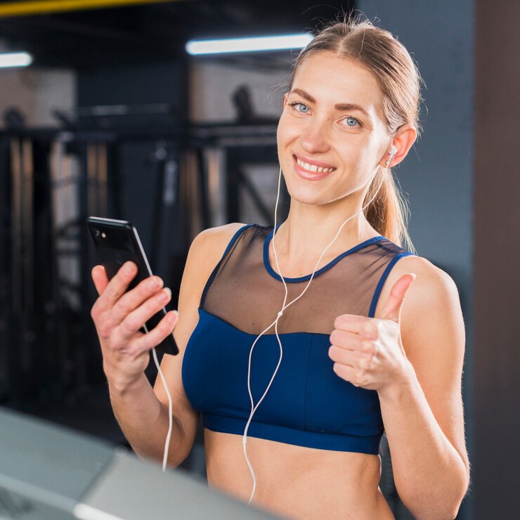 
A female personal trainer using her phone to choose music for an upcoming training session.
Source: Freepik