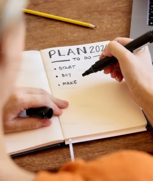 A woman writing in her calendar a plan for 2024 - what to start, buy and make in the fitness industry.