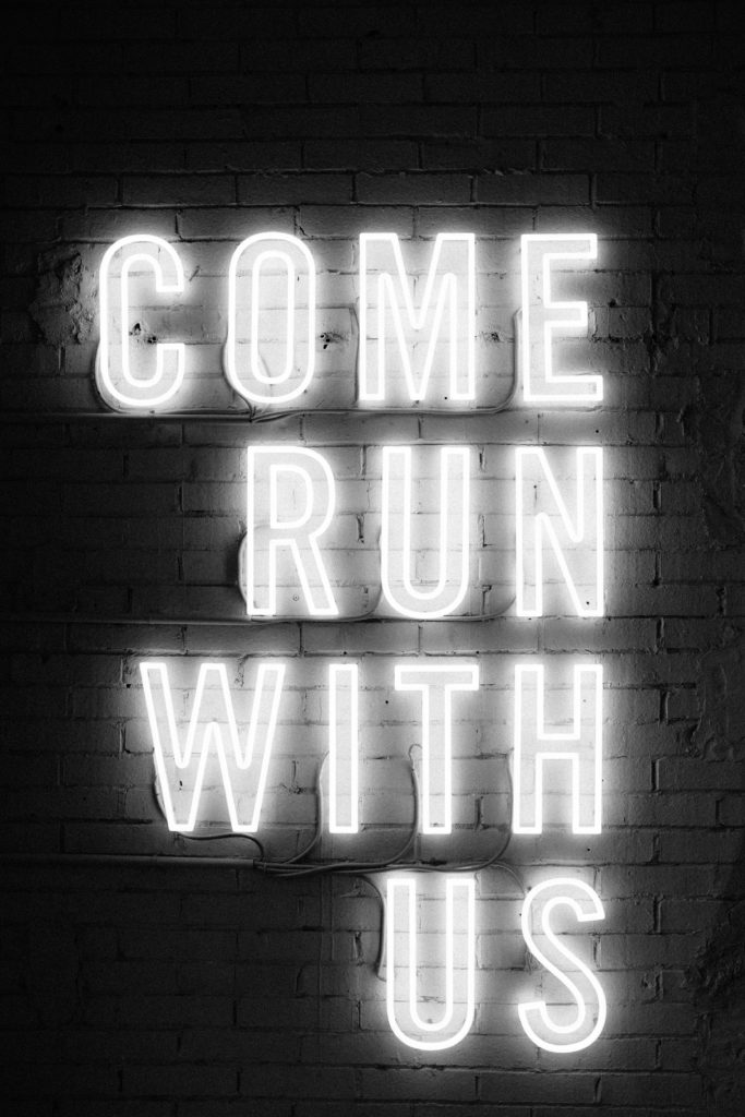 A motivational neon sign “Come run with us”.