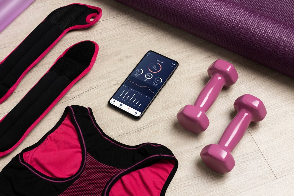 A mobile phone with a fitness app, dumbbells, mat and other fitness accessories. A perfect match for a training session.