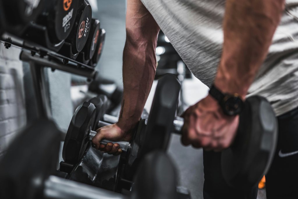 A man lifts dumbbells at the rack in Planet Fitness gym 