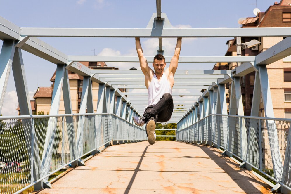 A young man having a gym training on a bridge, using its elements as fitness facilities.