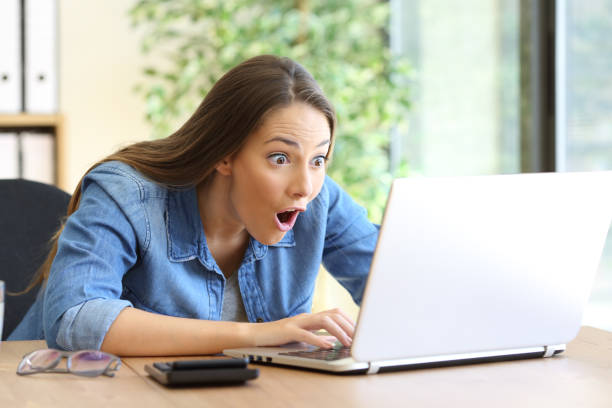 A woman looking at her computer and positively surprised by valuable content on one of the gym social media channels.