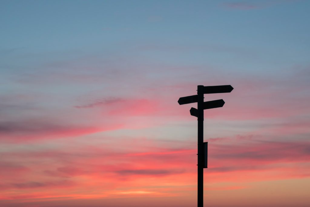 A sign with different directions to choose on a rising sun / sunset background. 