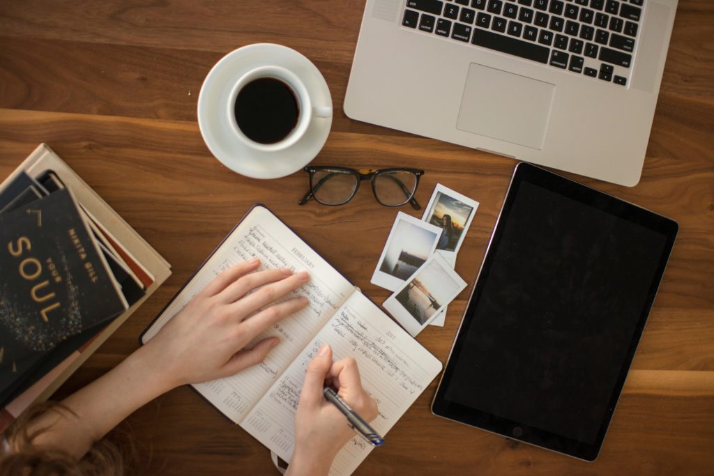 A woman, surrounded by inspiring materials, writing a yoga studio business plan.