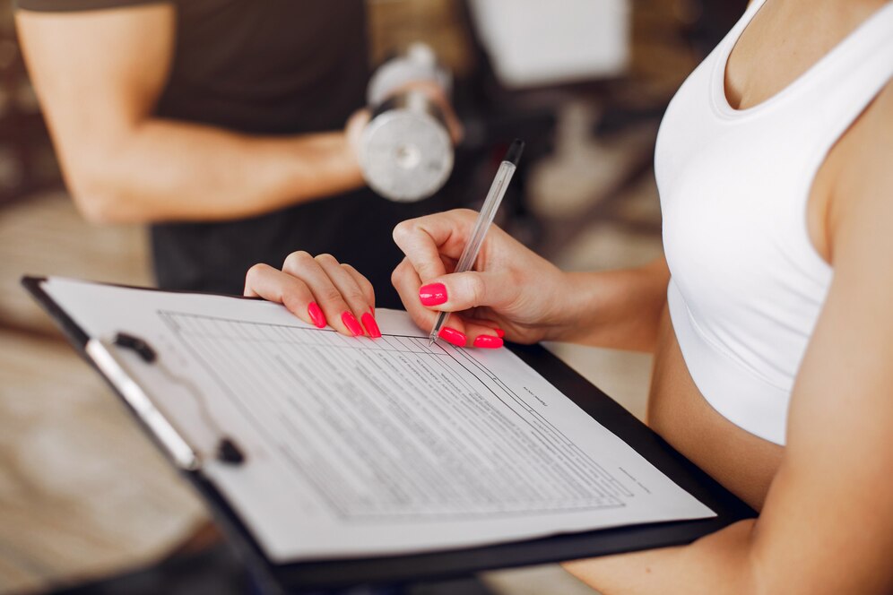 A female gym owner crossing out checkboxes during a personal training session. Source: Freepik