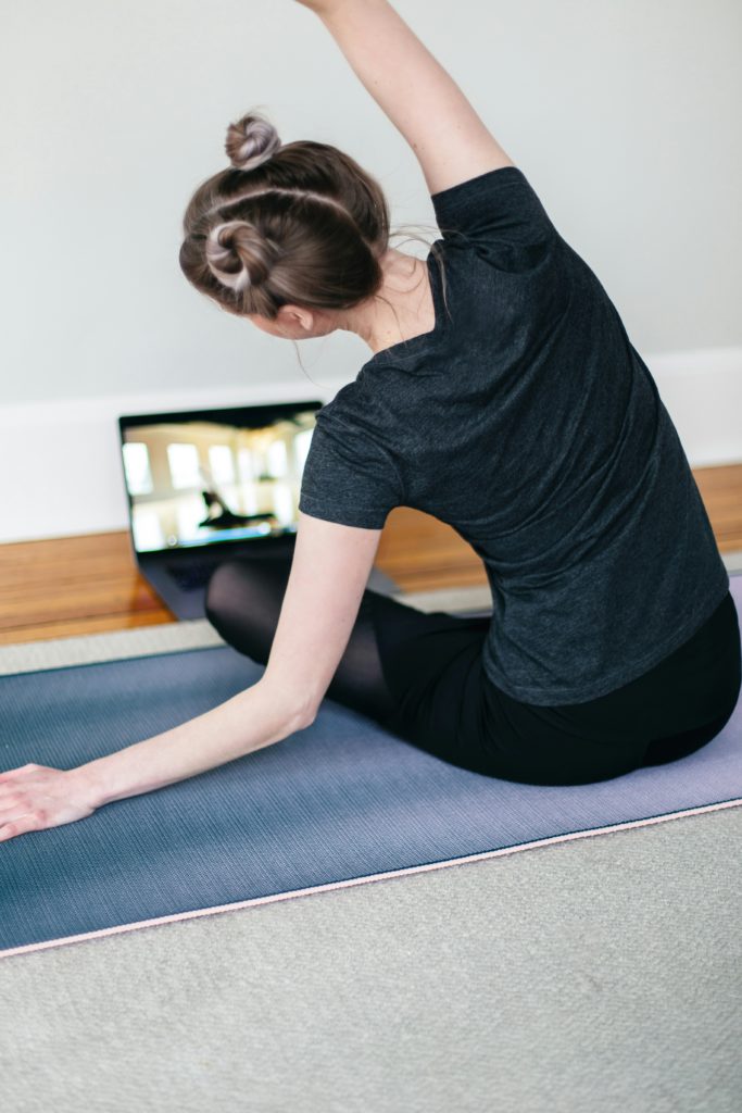 A woman practicing yoga online. Online lessons are also an idea for a yoga business. 