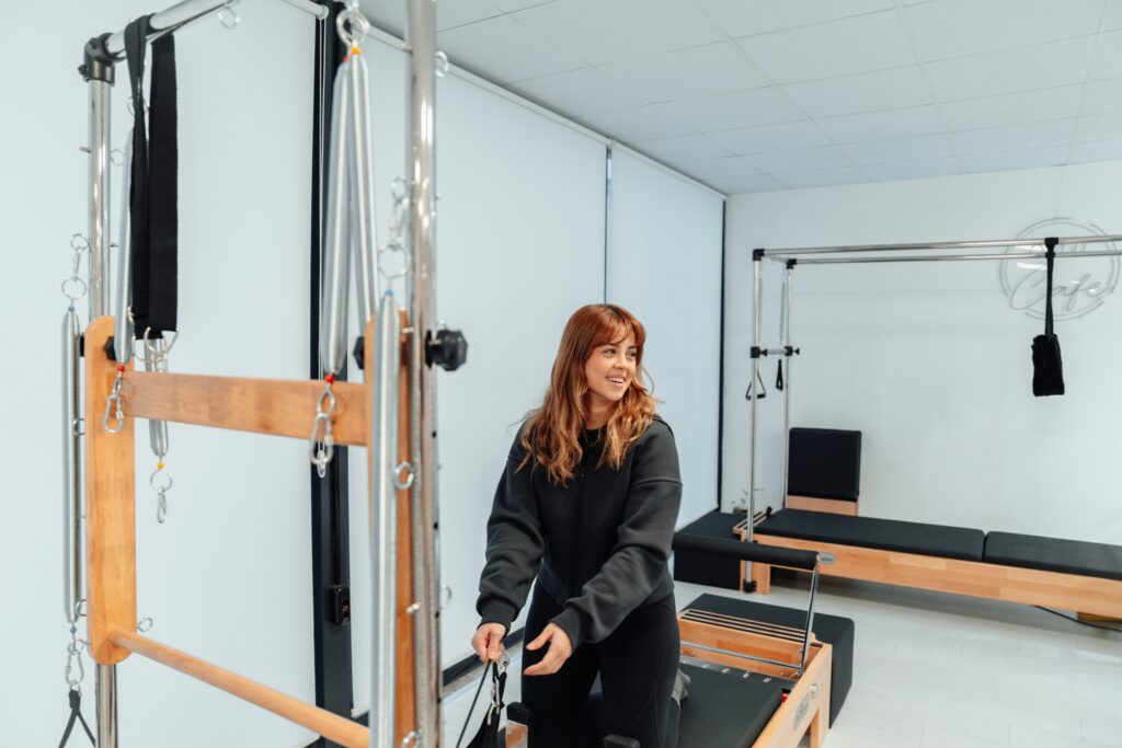 A pilates instructor showing an exercise on equipment during pilates classes.