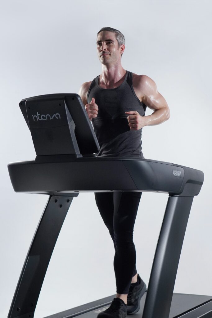 A man walking on a commercial gym standard treadmill.