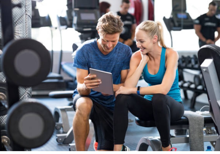 Gym members comparing their rewards program points on a tablet.