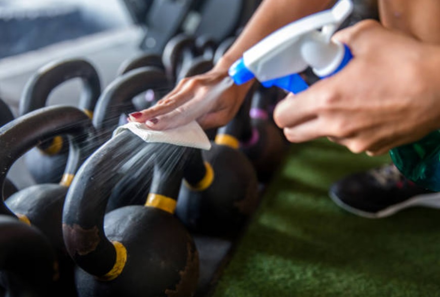 Regular cleaning of gym equipment with a general cleaning solution and a microfiber cloth.