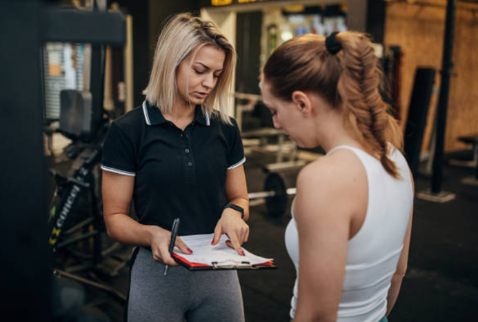 A liability waiver form used in the fitness industry is being shown to a client by a personal trainer.