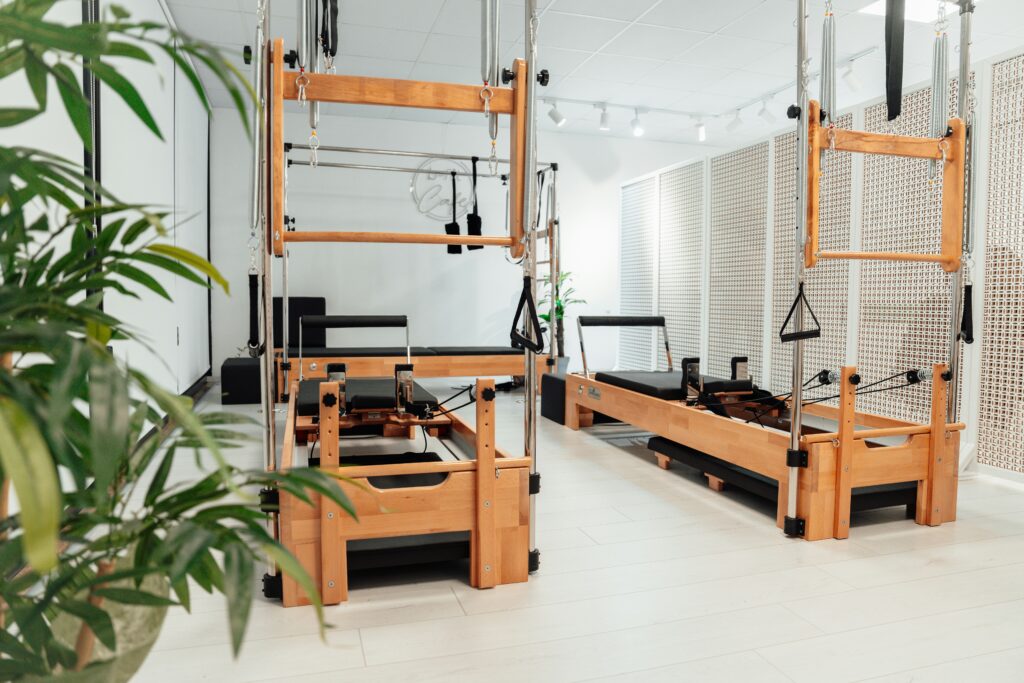 Pilates studio with reformers made of wooden elements and a plant standing on the floor to decorate the room, reflecting the idea of connection with nature and simplicity.