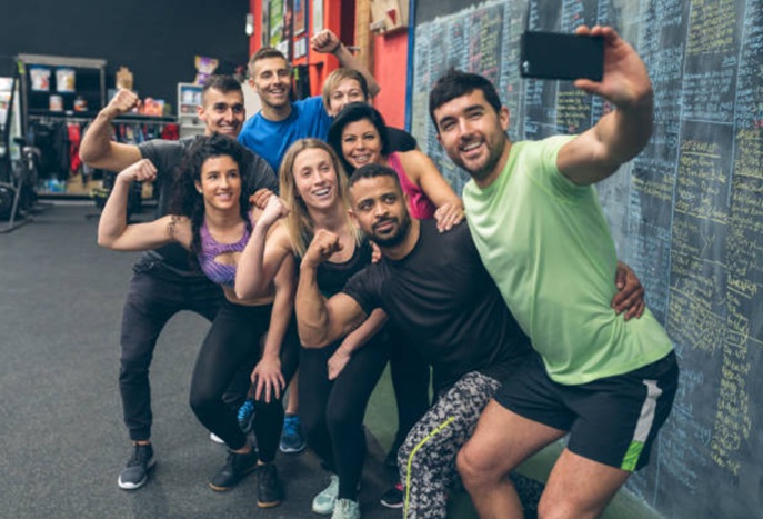 A group of actual humans engaged in fitness, smiling and spending time together at the gym - in contrast to remote contacts or AI interactions.